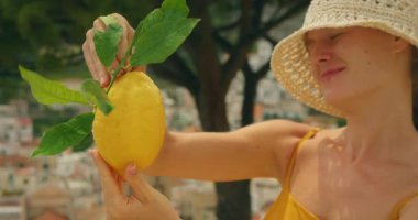 Gülümseyen kadın yaz günü arka planda Amalfi kasabasıyla birlikte büyük bir Sfusato limonu tutuyor..