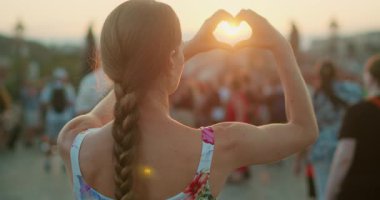 Prag 'daki Charles Köprüsü' nde kalabalık bir şehir meydanında kadın, gün batımında elleriyle bir kalp şekli oluşturuyor..