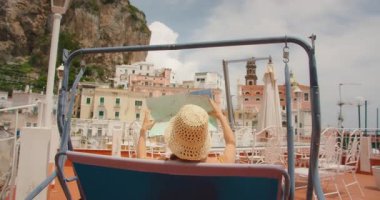 Elinde harita olan kadın İtalya 'daki şehir binalarına bakan terasta sallanıyor..