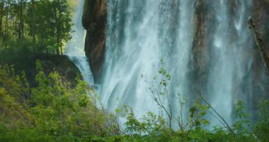Kayalık orman duvarına çarpan güçlü şelalenin yakın görüntüsü.