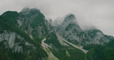 Gosau Gölü 'ndeki yemyeşil vadilerin üzerinde dumanla kaplı görkemli dağ zirveleri..