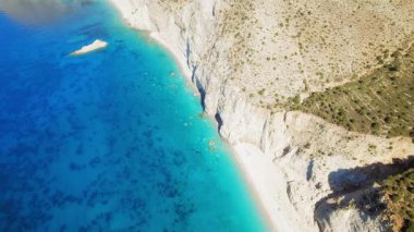 Yaz ışığında Kefalonia adasında parlak mavi sularla sarp kayalıklar..
