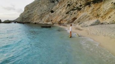 Güneş doğarken Kefalonia 'da sakin bir çakıl taşlı plajda duran bir kadın..