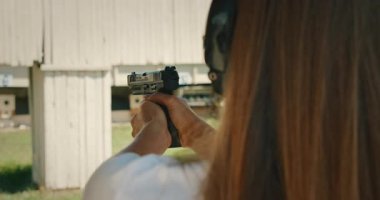 Elektronik kulaklıklı kadın atış menzilli hedeflere nişan alıyor ve ateş ediyor..