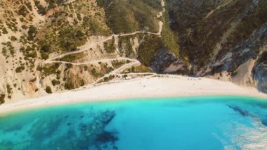 Yunanistan 'ın Kefalonia adasındaki verimli kayalıklarla kumlu sahil ve turkuaz deniz manzarası.
