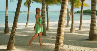 Kumlu sahilde çıplak ayaklı, palmiye ağaçları ve Meksika 'nın Yucatan Yarımadası' nda deniz manzaralı bir kadın..