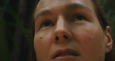 Yüzü koyu yemyeşil yağmur ormanlarında yukarı bakan bir kadın yüzü. Tropikal ormanlar..