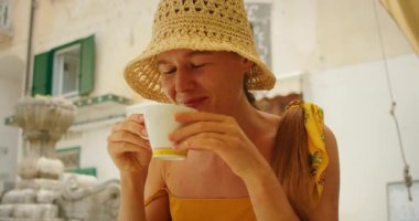 Hasır şapkalı gülümseyen kadın Atrani köyündeki kafede kahve içiyor..