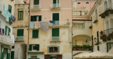 Atrani şehrinin merkezinde kirli çamaşırları asılı olan eski renkli binalar..