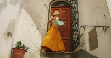 Amalfi kıyısındaki İtalyan köyü Atrani 'nin kırsal ahşap kapısının dışındaki haritayı kontrol eden kadın..