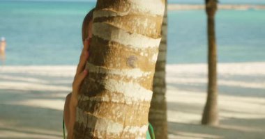 Riviera Maya Meksika 'da güneşli plajlara bakarken kadın nazikçe palmiye ağacına dokunur..