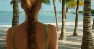 Yaz günü beyaz kum ve turkuaz denizle tropikal sahilde yürüyen bir kadın..