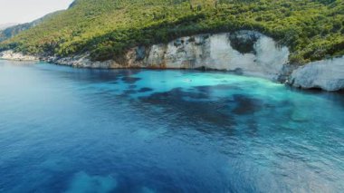 Turkuaz körfez, Kefalonia sahilinde demirlemiş teknesi olan orman kayalıklarıyla çevrili..