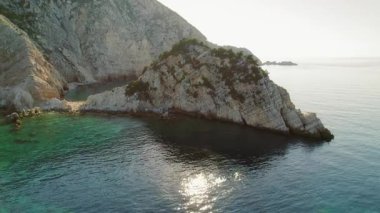 Yunanistan 'da sabah ışığı altında derin mavi denizle çevrili kaya oluşumu.