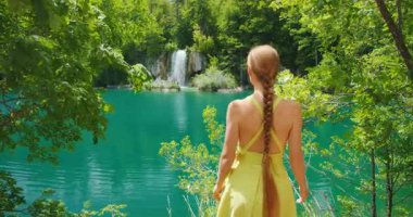 Hırvatistan 'daki Plitvice Gölleri Ulusal Parkı' ndaki orman patikasından şelaleye bakan kadın görülüyor.