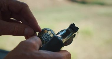 Atış mesafesinde bir silindire mermi dolduran adamın elleri..