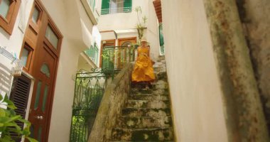 Atrani yerleşim bölgesindeki yosunlu taş merdivenlerden inen kadın..