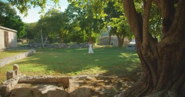 Ağaçlar ve Meksika 'daki Maya harabeleri arasında gölgeli bir çayırda yürüyen bir turist.