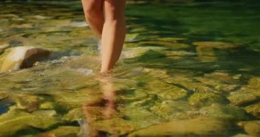 Çıplak bacaklar, yeşil yosunlu taşların üzerinden, sığ derede yürür. Cetina Nehri..