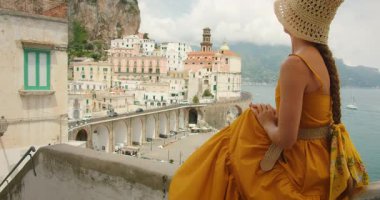 İtalya 'daki yükseltilmiş terastan Atrani şehrinin panoramik manzarasına hayran bir kadın..