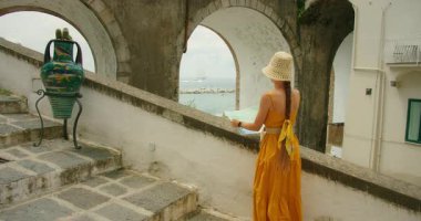 Haritalı turist İtalya 'nın kıyı kentinde Akdeniz' e kemer yoluyla bakıyor.