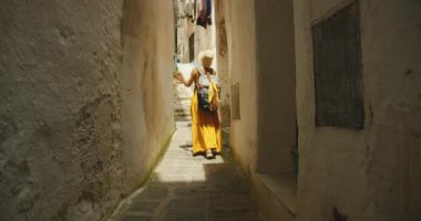 Sırt çantalı bir kadın Atrani 'de Amalfi kıyılarında dar bir sokak arşınlıyor..