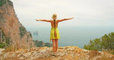 Capri 'de güneşli bir yaz gününde Faraglioni' nin manzarasının keyfini çıkaran kadın..