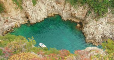 Yaz gezisi sırasında turkuaz deniz suyunda yüzen teknesi olan gizli kayalık koy..