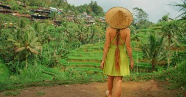 Yazlık elbiseli kadın güneşli bir günde Bali pirinç tarlalarına bakıyor..