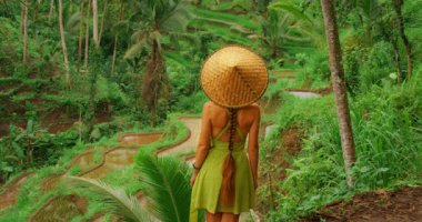 Yazın Bali 'de teraslara bakan hasır şapkalı bir kadın pirinç tarlaları görmüş..