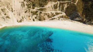 Beyaz kumlu Myrtos plajı, turkuaz suyu ve Kefalonia Yunanistan 'daki sarmal uçurum kenarı yolu..