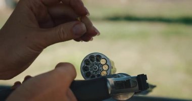 Atış poligonunda tabanca silindirine mermi dolduran kadının yakın çekim elleri..