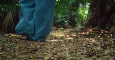 Tropikal ormanda, sık orman yaprakları arasında, çakıllı yolda yalınayak yürüyorum..