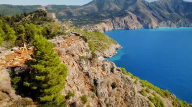 Yunanistan 'ın Kefalonya kentinde yaz aylarında deniz uçurumları ve dağların üzerinde yürüyen turistler.