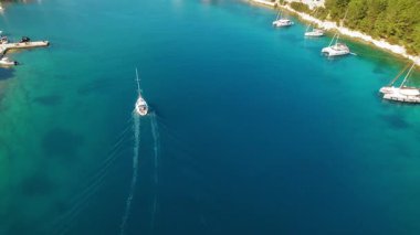 Yelkenli, güneşli bir yaz gününde Kefalonia 'daki mavi suyla Fiskardo limanına giriyor..