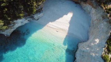 Kadın, kristal berrak suları ve Yunanistan 'da yaz güneşi altında sarp kayalıkları olan el değmemiş beyaz çakıl taşı plajında dinleniyor..