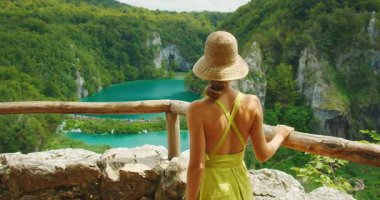 Plitvice Gölleri Ulusal Parkı Hırvatistan 'ın turkuaz sularına ve uçurumlarına şık giyinmiş genç bir bayan hayran..