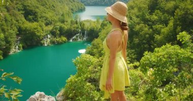 Güneşli yaz gününde Plitvice Parkı 'nda şelalelere ve göllere bakan bir kadın..