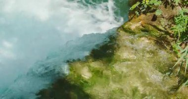 Güneşli yaz gününde Plitvice Lakes Ulusal Parkı 'ndaki yosunlu kayaların üzerinden akan temiz suyun yakın görüntüsü..