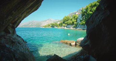 Hırvatistan 'ın turkuaz deniz ve kıyı kasabasına doğru açılan kayalık mağaranın manzarası.