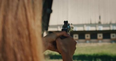 Atış poligonundaki hedeflere nişan alıp ateş eden bir kadın..