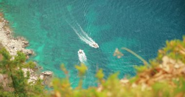 Capri İtalya 'nın kayalık kıyı şeridi yakınlarında turkuaz deniz sularında yüzen tekneler..