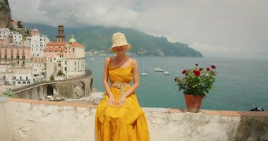 Atrani 'nin sahil köyü ve arka planında Amalfi Sahili' ne bakan denizle el ele tutuşan bir kadın..