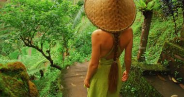 Yaz gezisi boyunca yeşil Bali pirinç teraslarında taş merdivenlerden inen bir kadın..