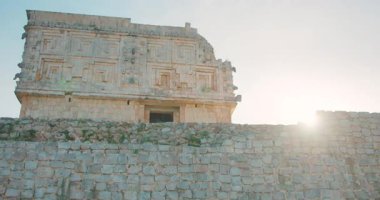 Eski Maya harabeleri, yıpranmış duvar oymalarıyla kare şeklindeki taş bina..