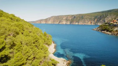 Kefalonya adasındaki Assos yakınlarındaki çam ağacı ormanları ve uçurumlar tarafından çerçevelenmiş körfez manzarası.