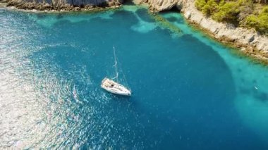 Kefalonia Yunanistan 'daki kayalıklarla çevrili açık mavi körfeze demirli yelkenli..