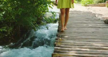 Çıplak ayaklı bir kadın yazın Plitvice 'de akıntıya karşı yürüyor..