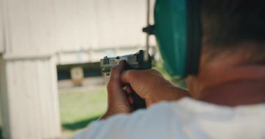 Atış talimi sırasında yarı otomatik tabancayı nişan alan ve ateşleyen adam..