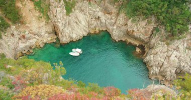 Capri Adası yaz mevsiminde turkuaz deniz suyuyla gizli kayalık koyda demirli eğlence gemileri..